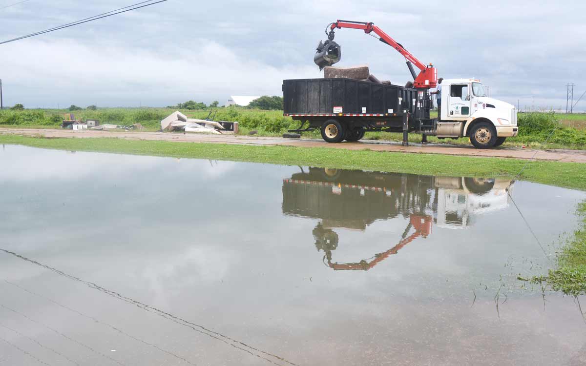 A City of Clarksdale knuckle-boom truck clears a flooded ditch on Sasse Street Thursday, June 10, 2021.
