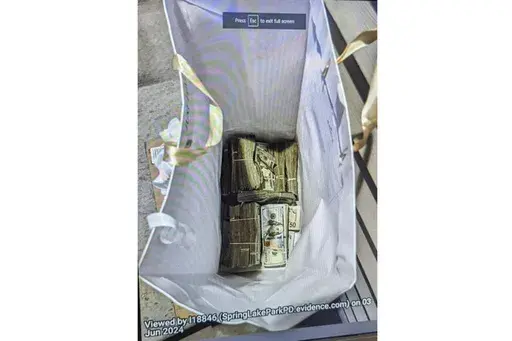 This photo supplied by the U.S. Attorney's Office for Minnesota shows cash from a bag that was left at the home of a juror in a massive fraud case, June 2, 2024, outside Minneapolis, Minn. Authorities have confiscated cellphones and taken all seven defendants into custody as investigators try to determine who attempted to bribe the juror to acquit them on charges of stealing more than $40 million from a program meant to feed children during the pandemic. (U.S. Attorney's Office for Minnesota via