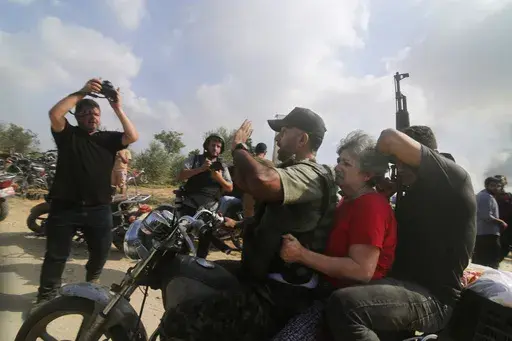 Palestinians transport a captured Israeli civilian, Adina Moshe, from her home in Kibbutz Nir Oz to the Gaza Strip, Oct. 7, 2023. The 72-year-old Israeli woman held captive by Hamas militants for nearly 50 days told an Israeli TV channel Wednesday, Jan. 24, 2024, that she was held at length in a dark, humid tunnel where she met Hamas’ leader and helped pass the time with a makeshift lecture series by her knowledgeable fellow hostages. (AP Photo, File)