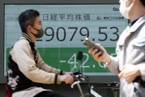 People walk in front of an electronic stock board showing Japan's Nikkei 225 index at a securities firm Thursday, May 11, 2023, in Tokyo. Asian shares were mixed in choppy trading Thursday after a report showed evidence that inflation in the United States was cooling, even if it remains too high. (AP Photo/Eugene Hoshiko)