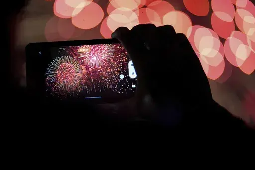 A spectator records a cell phone video as fireworks are launched over the Ohio River during the Western & Southern WEBN Fireworks show in Cincinnati on Sept. 3, 2023, in Cincinnati. (AP Photo/Aaron Doster)
