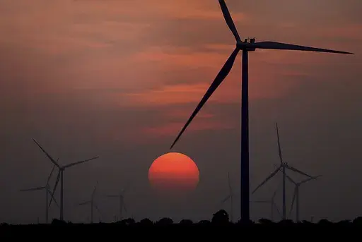 The sun sets at wind farm in McCook, Texas during a heat wave on July 20, 2022. Both sides of the political spectrum have their say about ESG: It’s either just a label that costs more, or it’s saving the world. Environmental, social and corporate governance criteria are factors for evaluating investments and companies, but have those criteria created any change? (Delcia Lopez/The Monitor via AP, File)