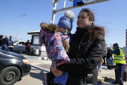 A woman carries her baby after fleeing the war from neighbouring Ukraine at the border crossing in Palanca, Moldova, Saturday, March 19, 2022. (AP Photo/Sergei Grits)