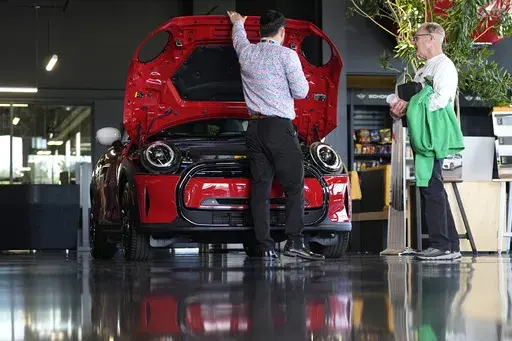 A salesperson shows an unsold 2024 Cooper SE electric hardtop to a prospective buyer at a Mini dealership Wednesday, May 1, 2024, in Highlands Ranch, Colo. On Friday, May 3, 2024, the U.S. government issues its April jobs report. (AP Photo/David Zalubowski)