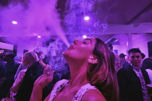 A guest takes a puff from a marijuana cigarette at the Sensi Magazine party celebrating the 420 holiday in the Bel Air section of Los Angeles, April 20, 2019. Marijuana advocates are gearing up for Saturday, April 20, 2024. Known as 4/20, marijuana's high holiday is marked by large crowds gathering in parks, at festivals and on college campuses to smoke together. This year, activists can reflect on how far the movement has come. (AP Photo/Richard Vogel, File)