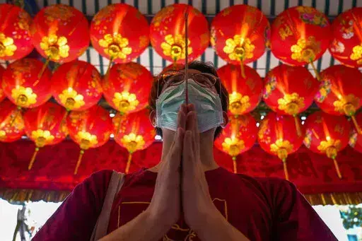 A person holds joss sticks while praying for good fortune on the eve of the Chinese Lunar New Year at Tai Hong Kong Shrine in Bangkok, Thailand, Monday, Jan. 31, 2022. The new year celebrations according to the lunar calendar will take place on Feb. 1. (AP Photo/Sakchai Lalit)