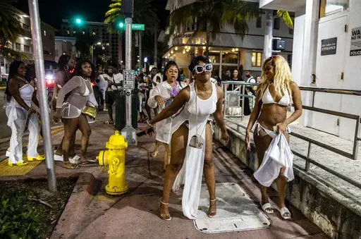 A group of women twerk on Washington Avenue early Saturday night before the midnight curfew imposed by the City of Miami Beach, Fla., Saturday March 26, 2022. Miami Beach officials have spent recent years trying to control the raucous crowds, public drinking and growing violence associated with the city's world-famous South Beach neighborhood during spring break. (Pedro Portal/Miami Herald via AP)