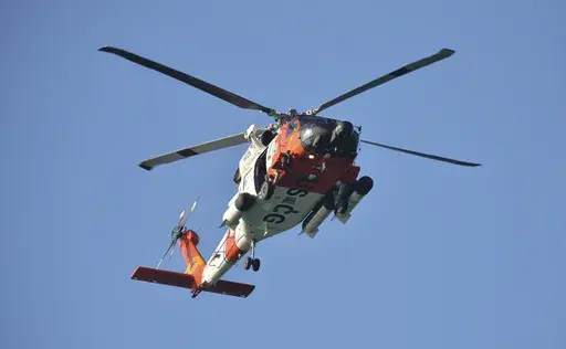 A U.S. Coast Guard helicopter flies over the Venice Fishing Pier Thursday morning, April 6, 2023, as emergency crews search a debris field in the Gulf of Mexico after a small airplane crash Wednesday night. Police say the bodies of two men and two women have been recovered following a small plane crash just off Florida's Gulf Coast. (Mike Lang/Sarasota Herald-Tribune via AP)