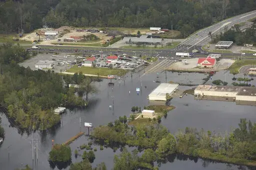 In this Monday, Sept. 24, 2018 photo, flood waters from the Neuse River cover the area a week after Hurricane Florence in Kinston, N.C. Monday Sept. 24, 2018.  Hot real estate markets have made some homeowners wary of participating in voluntary flood buyout programs, impacting efforts to move people away from flooding from rising seas, intensifying hurricanes and more frequent storms.  Flood buyout programs typically purchase flood-prone homes, raze them and turn the property into green space. (