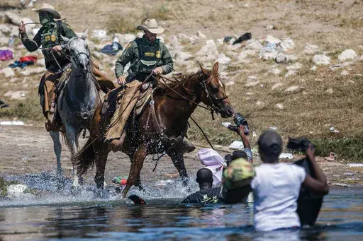 Mounted U.S. Border Patrol agents attempt to contain migrants as they cross the Rio Grande from Ciudad Acuña, Mexico, into Del Rio, Texas, Sept. 19, 2021. Border Patrol agents on horseback engaged in "unnecessary use of force" against non-threatening Haitian immigrants but didn't whip any with their reins, according to a federal investigation of chaotic scenes along the Texas-Mexico border last fall. (AP Photo/Felix Marquez, File)