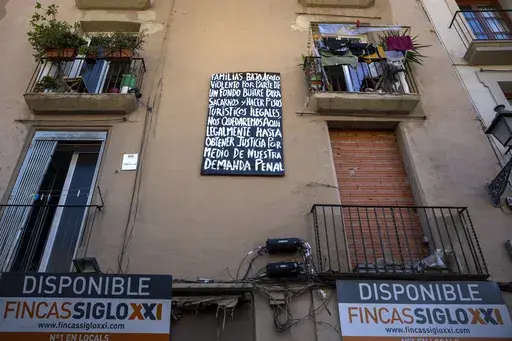 A block of flats, which is under threat of eviction, is photographed in downtown Barcelona, Spain, Wednesday, July 10, 2024. Barcelona City Hall announced last month that it would not renew any tourist apartment licenses after they expire in 2028. The banner reads in Spanish: Families who are under violent harassment by a vulture fund to evict us and make illegal tourist flats, we will stay here until we get justice through our criminal lawsuit. (AP Photo/Emilio Morenatti)