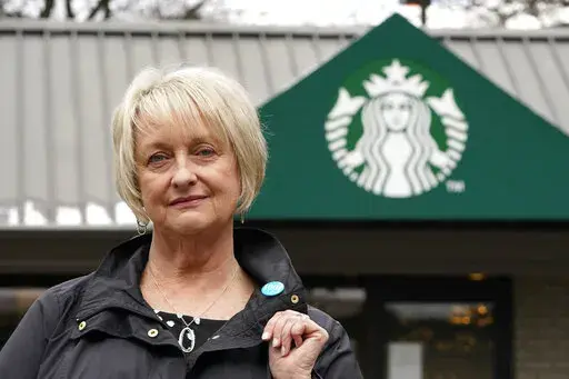 Pam Blauman-Schmitz, who was a union rep at Starbucks in the mid-1980's, poses for a photo in front of a Starbucks coffee shop Tuesday, Feb. 22, 2022, in Seattle. Starbucks, now facing union elections at more than 100 U.S. stores, has spent decades fighting unionization. (AP Photo/Elaine Thompson)