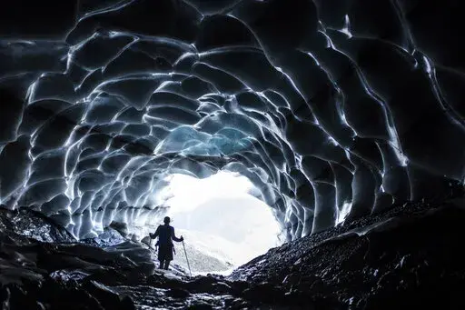 A man stands in a glacier cave at the Sardona glacier, July 27, 2022, in Vaettis, Switzerland. The melting glacier has revealed a cave. Faced with increasing demand for alpine water resources at a time of accelerating glacier melt, policymakers from 8 European countries are meeting in Switzerland to prevent a dispute over diminishing water resources from the highest peaks in the Alps. (Gian Ehrenzeller/Keystone via AP, File)