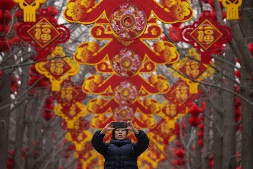 A woman takes a picture of red lanterns and decorations on display along the trees ahead of the Chinese Lunar New Year at Ditan Park in Beijing, Feb. 4, 2024. In many Asian cultures, the Lunar New Year is a celebration marking the arrival of spring and the start of a new year on the lunisolar calendar. It's the most important holiday in China where it's observed as the Spring Festival. (AP Photo/Andy Wong, file)
