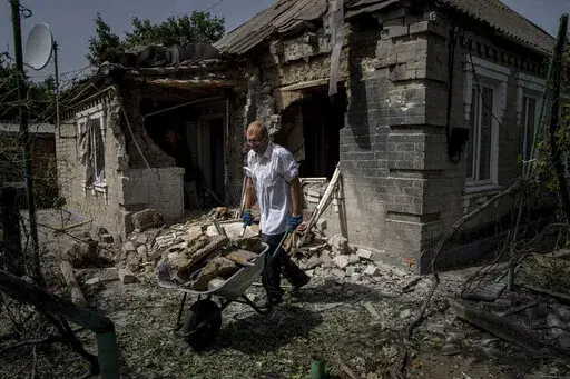 Dmyto Shengur cleans rubble in front of the house which was damaged after Russian bombardment of residential area in Nikopol, Ukraine, on Monday, Aug, 22, 2022. In Nikopol, across the river from Ukraine's main nuclear power plant, Russian shelling wounded four people Monday, an official said. The city on the Dnipro River has faced relentless pounding since July 12 that has damaged some 850 buildings and sent about half its population of 100,000 fleeing. (AP Photo/Evgeniy Maloletka)