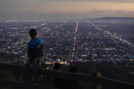 A boy takes in the view of the Los Angeles skyline from the Griffith Park Observatory Trails Peak in Los Angeles, Monday, Nov. 14, 2022. The 8 billionth baby on Earth is about to be born on a planet that is getting hotter. But experts in climate science and population both say the two issues aren't quite as connected as they seem. (AP Photo/Jae C. Hong)