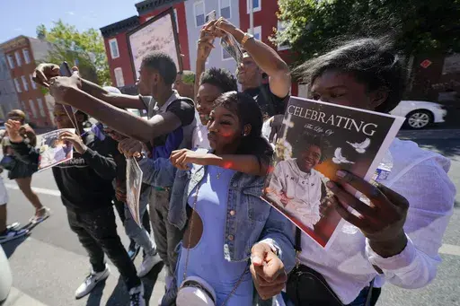A photograph of Antonio Lee is seen on a program as mourners gather for photographs following a funeral service for Lee, Thursday, Aug. 31, 2023, in Baltimore. Lee, 19, a squeegee worker was killed during a shooting as he panhandled in a Baltimore street corner. (AP Photo/Julio Cortez)