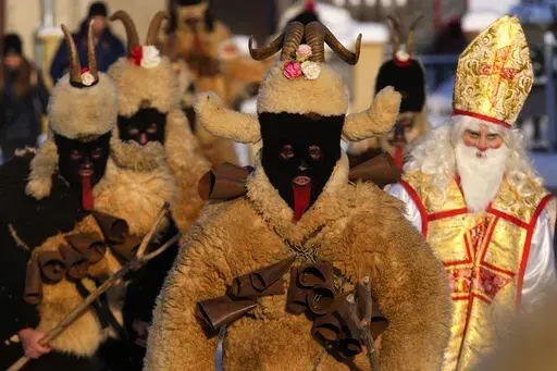 Revelers take part in a traditional St. Nicholas procession in the village of Lidecko, Czech Republic, Monday, Dec. 4, 2023. This pre-Christmas tradition has survived for centuries in a few villages in the eastern part of the country. The whole group parades through the village for the weekend, going from door to door. St. Nicholas presents the kids with sweets. The devils wear home-made masks of sheep skin and the white creatures representing death with scythes frighten them. (AP Photo/Petr Dav