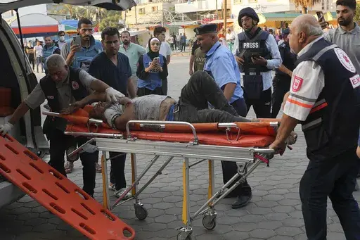 Journalists observe as a Palestinian man wounded in Israeli bombardment is brought to a hospital in Deir el-Balah, Gaza Strip, Monday, Oct. 16, 2023. Journalists reporting in Gaza need to worry about basic survival for themselves and their families in addition to getting out the story of a besieged population. (AP Photo/Adel Hana, File)