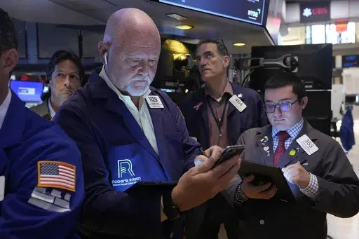 Robert Moran, left, works with fellow traders on the floor of the New York Stock Exchange, Friday, Aug. 16, 2024. (AP Photo/Richard Drew, File)