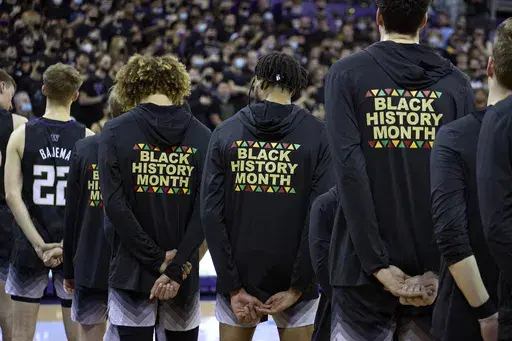 Washington players stand during the playing of the national anthem wearing warm-up jackets for Black History Month before an NCAA college basketball game against Arizona, Feb. 12, 2022, in Seattle. (AP Photo/John Froschauer, File)