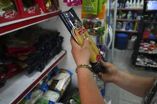 A man looks at a pack of pasta at a grocery store in Tehran, Iran, Wednesday, May 11, 2022. Iran abruptly raised prices as much as 300% for a variety of staples such as cooking oil, chicken, eggs and milk on Thursday. (AP Photo/Vahid Salemi)