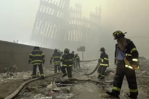 In this Sept. 11, 2001 photo, firefighters work beneath destroyed mullions, the vertical struts which once faced the outer walls of the World Trade Center towers, after a terrorist attack on the twin towers in New York. (AP Photo/Mark Lennihan, File)