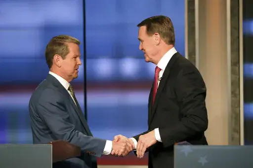 Georgia Gov. Brian Kemp, left, shakes hands with former Sen. David Perdue at a Republican gubernatorial debate, Sunday, April 24, 2022, in Atlanta. (Miguel Martinez/Atlanta Journal-Constitution via AP)