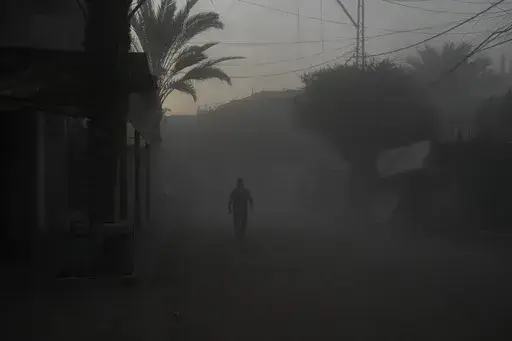 A Palestinian walks on a smoke-filled street after an Israeli airstrike in Deir al Balah, Gaza Strip, Tuesday, Aug. 6, 2024. (AP Photo/Abdel Kareem Hana)