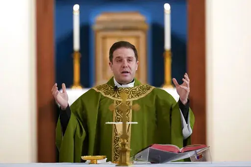 Father Matthew Hood celebrates mass at Our Lady of the Rosary church Friday, Feb. 18, 2022, in Detroit. In 2020, one word caught the ear of a young Detroit-area Catholic priest while he watched a video of his baptism from decades earlier. "Wait," the Rev. Matthew Hood recalled thinking. "Something doesn't seem right here." Indeed, an error by a deacon had spoiled the sacrament — and, in domino-like fashion, meant he truly wasn't a priest. (AP Photo/Paul Sancya)