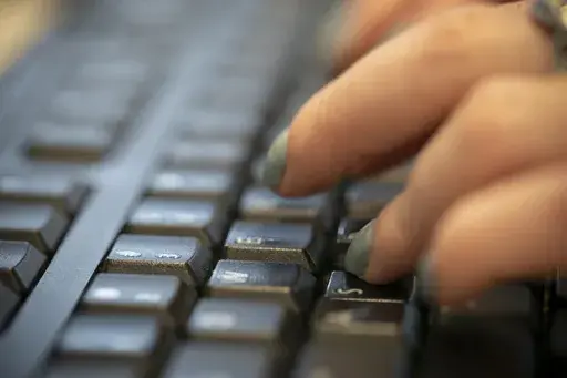 A woman types on a keyboard in New York, Oct. 8, 2019. A good strategy to protect yourself from financial scams is to verify the identity of anyone who contacts you and claims to be your bank by hanging up and placing a call to a confirmed number yourself. (AP Photo/Jenny Kane, File)