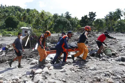 Rescuers carry a body at Maguindanao's Datu Odin Sinsuat town, southern Philippines on Sunday Oct. 30, 2022. Victims of a huge mudslide set off by Tropical Storm Nalgae in a coastal Philippine village that had once been devastated by a killer tsunami mistakenly thought a tidal wave was coming and ran to higher ground toward a mountain and were buried alive, an official said Sunday. (AP Photo)