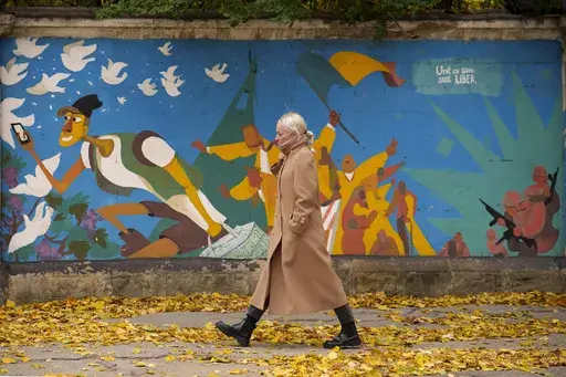 A woman walks by graffiti done in 2016 by Moldovan artists celebrating 25 years since the country declared its independence from the Soviet Union, in Chisinau, Moldova, Monday, Nov. 4, 2024. (AP Photo/Vadim Ghirda)