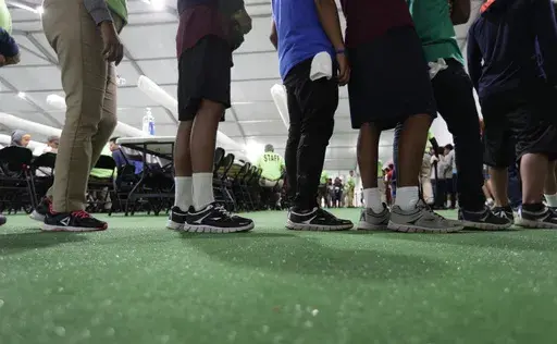 Immigrants line up in the dining hall at a U.S. government holding center for migrant children, July 9, 2019, in Carrizo Springs, Texas. (AP Photo/Eric Gay, File)