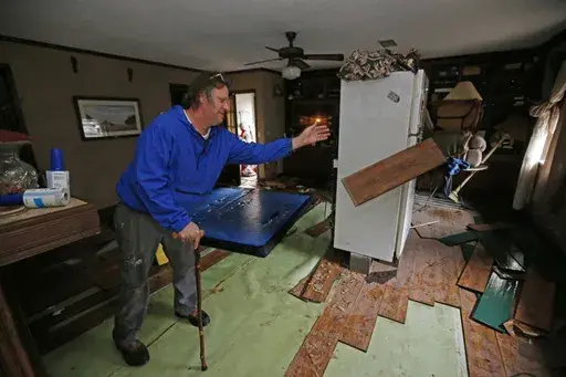 FILE-Jeff Sharp tosses flood-damaged flooring into a pile Feb. 19, 2020, as he helps his brother clean up after the Pearl River sent water into homes in Jackson, Miss. The U.S. Army Corps of Engineers in August 2024 is wrapping up a public comment period on its proposals for flood control measures in the Jackson area, and the agency could make final recommendations by the end of the year. (AP Photo/Rogelio V. Solis, File)
