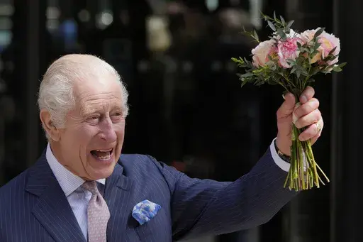 Britain's King Charles III holds up flowers he was given as he leaves after a visit to University College Hospital Macmillan Cancer Centre in London, Tuesday, April 30, 2024. (AP Photo/Kin Cheung)