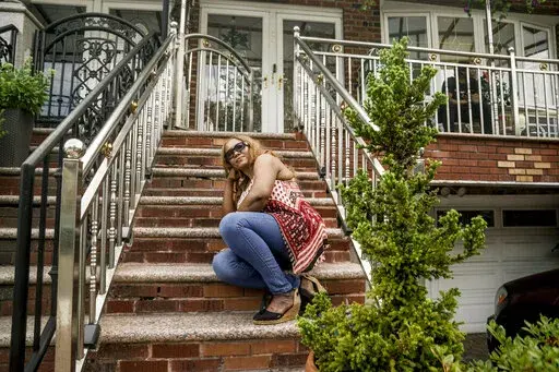 Rose Prophete sits outside on the steps of her brick townhouse, Thursday, July 28, 2022, in the Brooklyn borough of New York. Prophete, a hospital technician who immigrated from Haiti in February 2000, was blindsided with a foreclosure action on the home she worked three jobs to buy and said "I will fight until my last breath." (AP Photo/Bebeto Matthews)