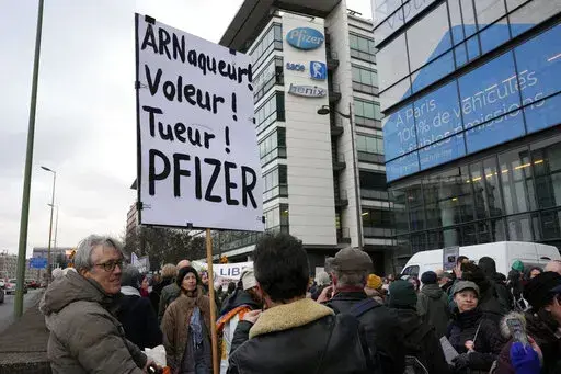 A demonstrator holds a placard reading "Scammer, thief, killer, Pfizer" during a protest against the vaccine pass and vaccinations to protect against COVID-19 in front of the Pfizer headquarters, in Paris, on Jan. 29, 2022. An anti-vaccine group that has harassed doctors and public officials in Italy and France is still active on platforms like Facebook despite efforts to rein in their abuse and misinformation. The organization, known as V_V, bombards its victims with dozens, hundreds or even th