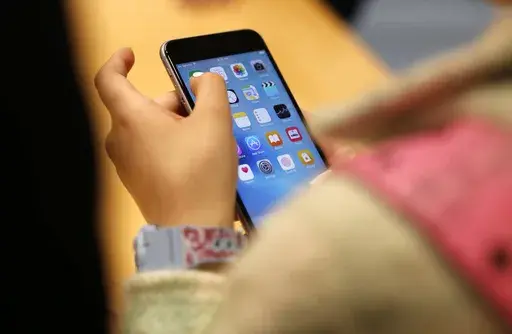 A child holds an iPhone at an Apple store on Sept. 25, 2015 in Chicago. Parents — and even some teens themselves — are growing increasingly concerned about the effects of social media use on young people. (AP Photo/Kiichiro Sato, File)