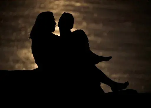 In this June 27, 2018, file photo a couple is silhouetted against moonlight reflecting off the Missouri River as they watch the full moon rise beyond downtown buildings in Kansas City, Mo. Money can create stress within a relationship, but talking through expectations and money beliefs can help couples get on the same page. In fact, conflict over money can be healthy, partly because we often partner with people who are our financial opposites. (AP Photo/Charlie Riedel, File)
