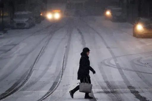 A commuter braves the wind and snow in frigid weather, Jan. 30, 2019, in Cincinnati. (AP Photo/John Minchillo, File)