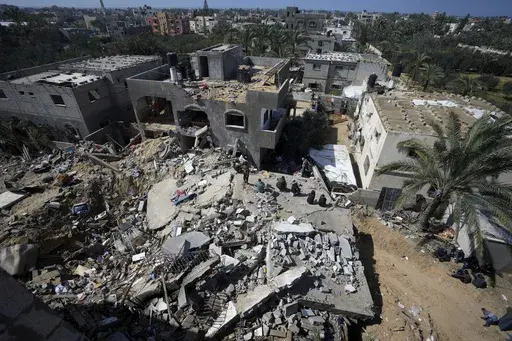 Palestinians look at destruction after an Israeli airstrike on a residential building of the Ganan family in Deir al Balah, Gaza Strip, Thursday, March 7, 2024. (AP Photo/Adel Hana)