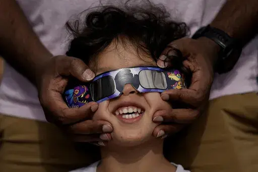 Viewers use special glasses to watch from San Antonio, as the moon moves in front of the sun during an annular solar eclipse, or ring of fire, Oct. 14, 2023. The total solar eclipse on April 8, 2024 may be weeks away but businesses are ready for the celestial event with oodles of special eclipse glasses for sale, along with T-shirts and other souvenirs. (AP Photo/Eric Gay, File)