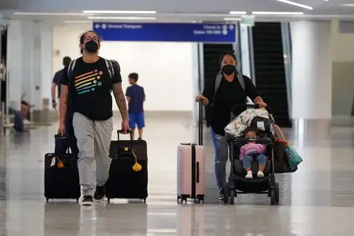 Travelers roll their luggage at a baggage claim area at Los Angeles International Airport Monday, April 25, 2022, in Los Angeles. Traveling with kids is expensive — and hard. You need to budget for extra airfare, a bigger rental car and additional lodging, plus account for naps, snacks, tantrums and blowouts when packing and planning your itinerary.   (AP Photo/Marcio Jose Sanchez, File)
