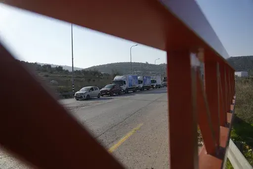 Palestinian motorists waiting in line at the Ein Senia Israeli army checkpoint are seen through an iron gate north of the West Bank city of Ramallah, Wednesday, Jan. 29, 2025. (AP Photo/Nasser Nasser)