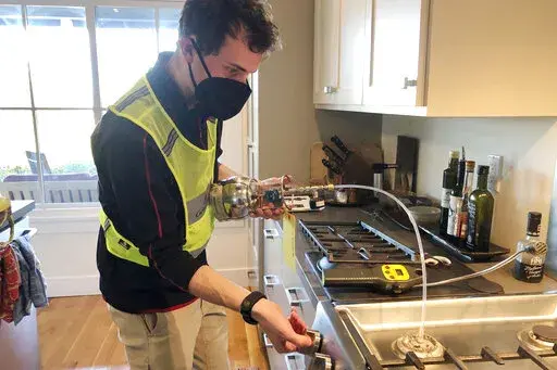 In this photo provided by climate scientist Rob Jackson, researcher Eric Lebel samples natural gas from a stove in Stanford, Calif., in 2021. According to a study published Thursday, Jan. 27, 2022, in the journal Environmental Science & Technology, gas stoves are worse for the climate than previously thought because of constant tiny methane leaks even while they’re off. (Rob Jackson via AP)