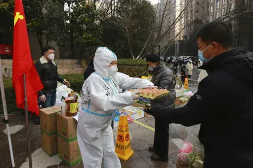 A community volunteer hands over eggs to a buyer at a temporary food store to provide supplies to residents outside a residential block in Xi'an city in northwest China's Shaanxi province Monday, Jan. 03, 2022. Authorities in the northern Chinese city of Xi'an say they can provide food, health care and other necessities for the roughly 13 million under an almost two-week old lockdown. But some residents describe difficulties obtaining supplies and frustration and the economic impact on the city 