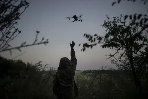 A Ukrainian drone pilot reaches for a reconnaissance drone in the Luhansk Region, Ukraine, Saturday, Aug. 19, 2023. The drone unit's task is to destroy Russia's heavy machinery, armored vehicles and infantry. (AP Photo/Bram Janssen)
