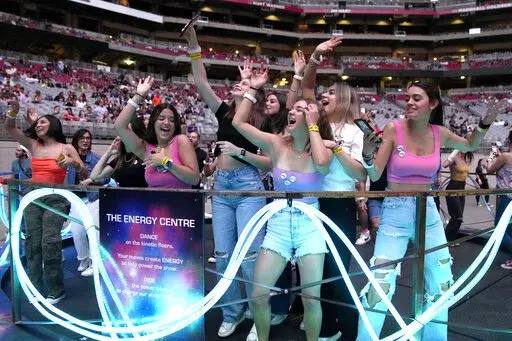 Concertgoers dance during Coldplay's Music of the Spheres world tour on Thursday, May 12, 2022, at State Farm Stadium in Glendale, Ariz. The band has included energy-storing stationary bikes to their latest world tour, encouraging fans to help power the show as part of a push to make the tour more environmentally friendly. (Photo by Rick Scuteri/Invision/AP)