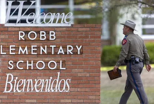 A state trooper walks past the Robb Elementary School sign in Uvalde, Texas, Tuesday, May 24, 2022, following a deadly shooting at the school. (William Luther/The San Antonio Express-News via AP, File)